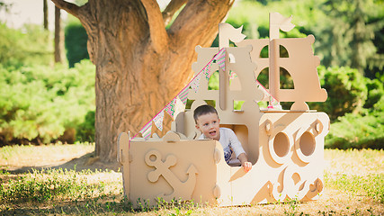 Image showing Boy playing in cardboard boat at park.