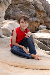 Image showing Happy child relaxes on rocks