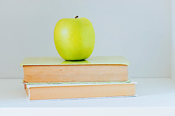 Image showing A yellow apple sitting on top of a stack of books