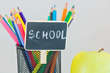 Image showing Yellow apple and pencils in holder