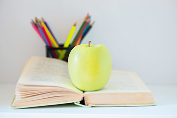 Image showing A yellow apple sitting on opened book