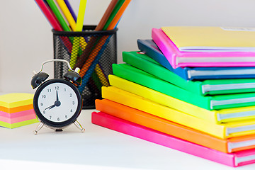 Image showing Black alarm clock and multi colored books in stack