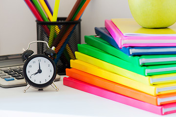 Image showing Black alarm clock and multi colored books in stack