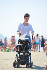 Image showing mother walking on beach and push baby carriage