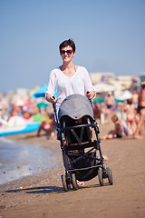 Image showing mother walking on beach and push baby carriage