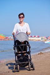 Image showing mother walking on beach and push baby carriage