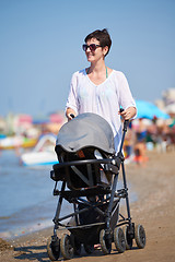 Image showing mother walking on beach and push baby carriage