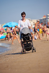 Image showing mother walking on beach and push baby carriage