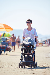 Image showing mother walking on beach and push baby carriage