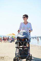 Image showing mother walking on beach and push baby carriage