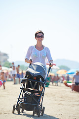 Image showing mother walking on beach and push baby carriage