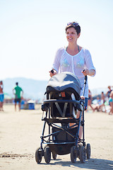 Image showing mother walking on beach and push baby carriage