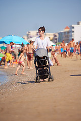 Image showing mother walking on beach and push baby carriage