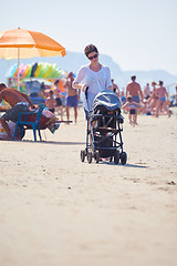 Image showing mother walking on beach and push baby carriage