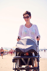 Image showing mother walking on beach and push baby carriage