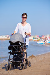 Image showing mother walking on beach and push baby carriage