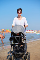 Image showing mother walking on beach and push baby carriage