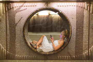 Image showing Young woman using smart phone on bench.