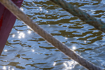 Image showing Mooring line of a trawler in backlight with water reflections