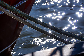 Image showing Mooring line of a trawler in backlight with water reflections