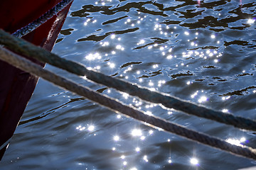 Image showing Mooring line of a trawler in backlight with water reflections