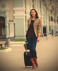 Image showing beautiful business woman with a suitcase walking on the apron la