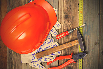 Image showing aged hammer, pliers, screwdriver, tape measure, a bright helmet 