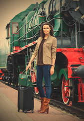 Image showing adult woman traveler with a suitcase near the vintage steam loco