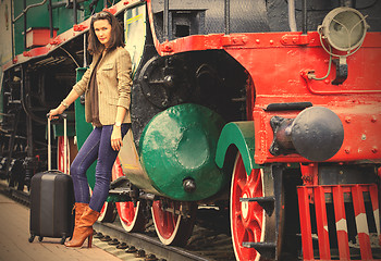 Image showing woman traveler with a suitcase near the old steam locomotive