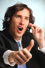 Image showing young handsome long hair operator with headset doing sucsess ges