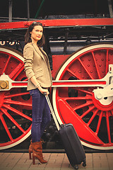 Image showing woman with a suitcase near the huge locomotive wheels