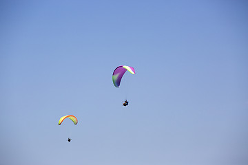 Image showing Colorful paragliders with blue sky