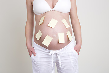 Image showing Pregnant woman with lots of yellow labels on her belly