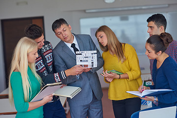 Image showing group of students working with teacher on  house model