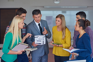 Image showing group of students working with teacher on  house model