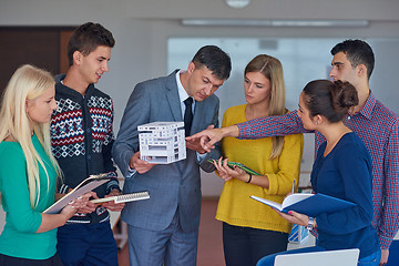 Image showing group of students working with teacher on  house model