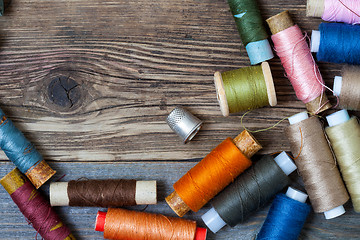 Image showing thimble and spools of thread on an aged wooden surface