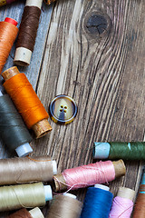 Image showing Vintage spools with multi colored threads and old button