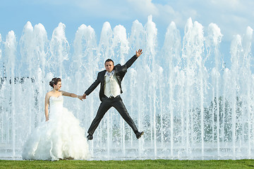 Image showing Groom jumping in front of water fountain