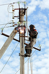 Image showing Electrician connects metal parts ground loop on a pole transmiss