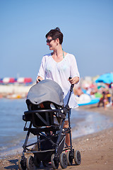 Image showing mother walking on beach and push baby carriage