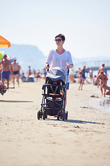 Image showing mother walking on beach and push baby carriage