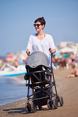 Image showing mother walking on beach and push baby carriage