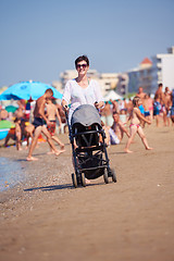 Image showing mother walking on beach and push baby carriage