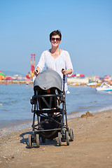 Image showing mother walking on beach and push baby carriage