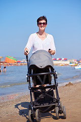 Image showing mother walking on beach and push baby carriage