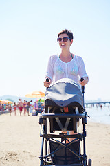 Image showing mother walking on beach and push baby carriage