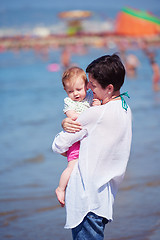 Image showing mother walking on beach and push baby carriage