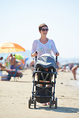 Image showing mother walking on beach and push baby carriage