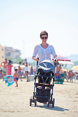 Image showing mother walking on beach and push baby carriage